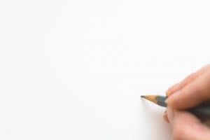 Person holding pencil against paper about to begin writing