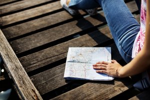 A woman sitting on a dock, holding a map beside her