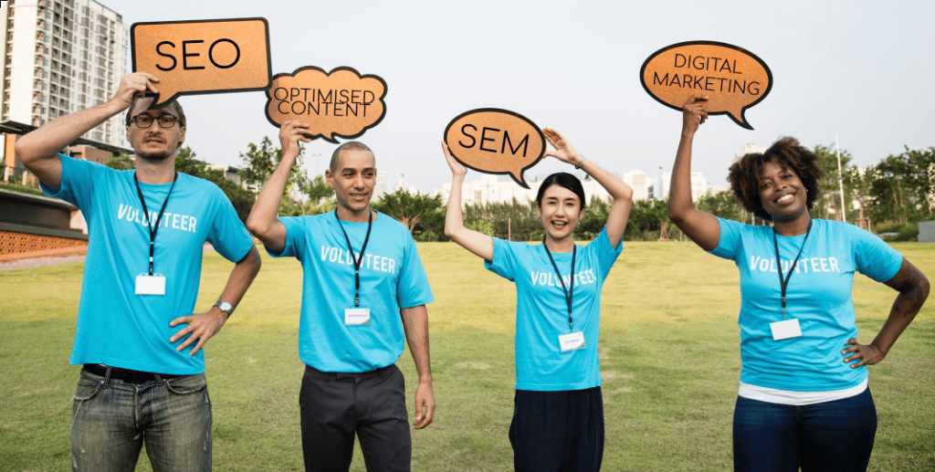 Four charity volunteers with blue shirts holding SEO banners above their heads 